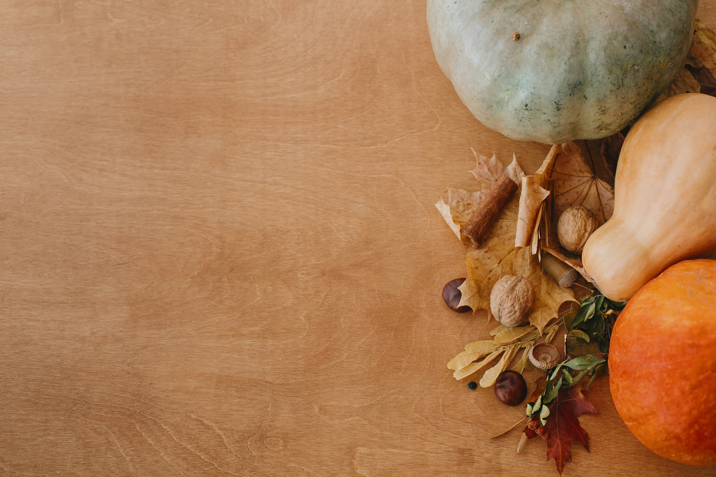 Happy Thanksgiving. Pumpkins, autumn leaves, corn, walnuts,chestnuts,acorns border on rustic wooden table. Flat lay with space for text. Autumn seasonal harvest. Hello fall